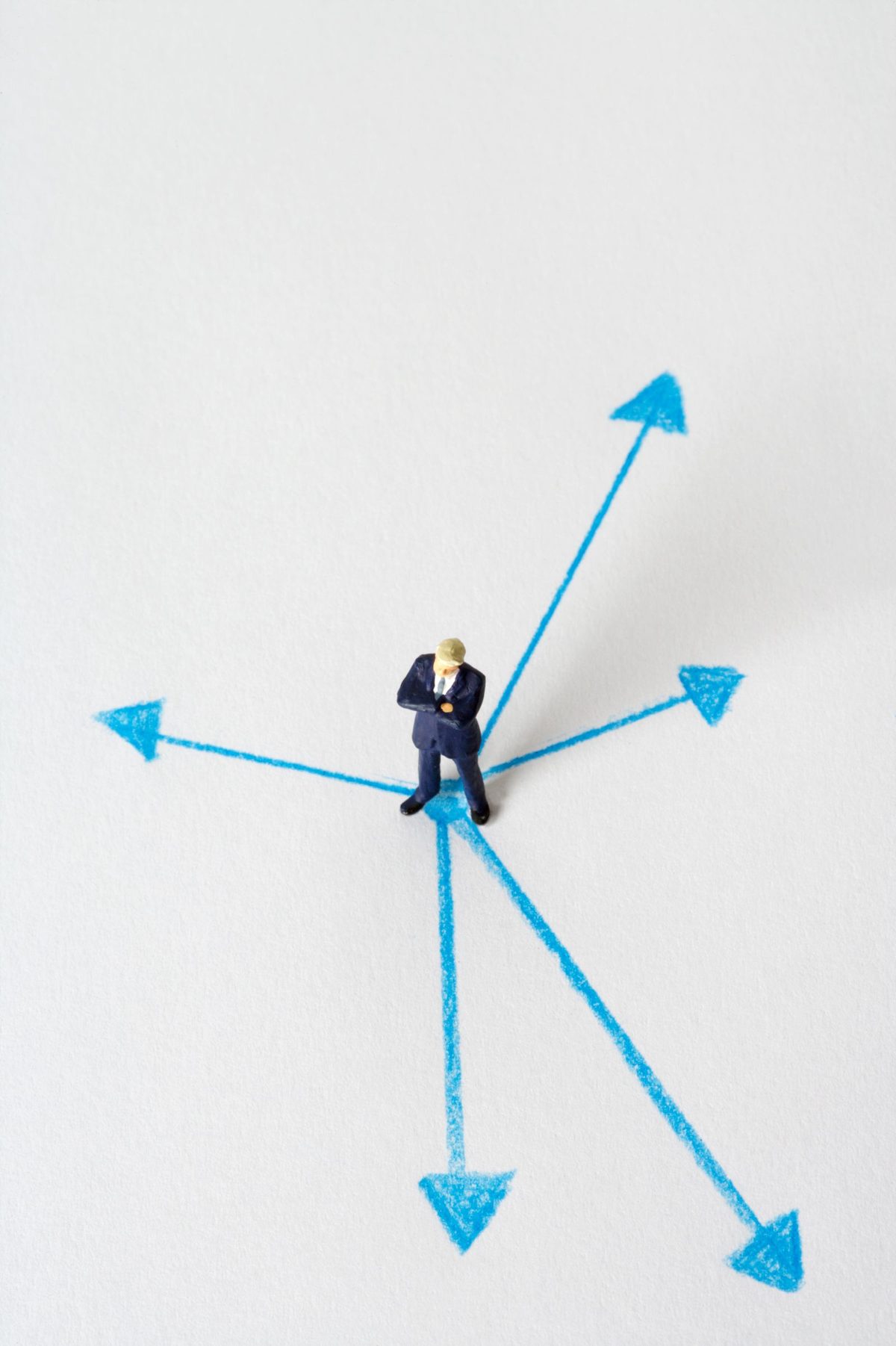 Miniatura de executivo em um cruzamento de caminhos, representando uma decisão de negócio