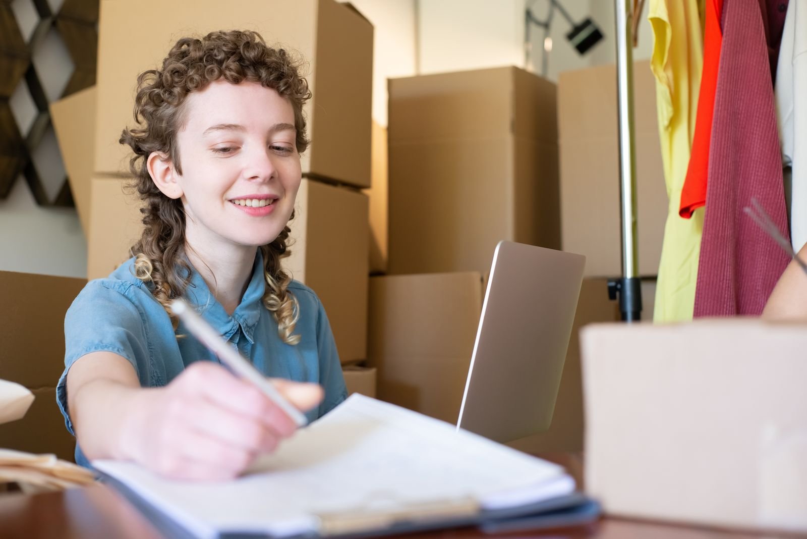 Empreendedora organiza pedidos de sua loja online sozinha, cercada de caixas de envio