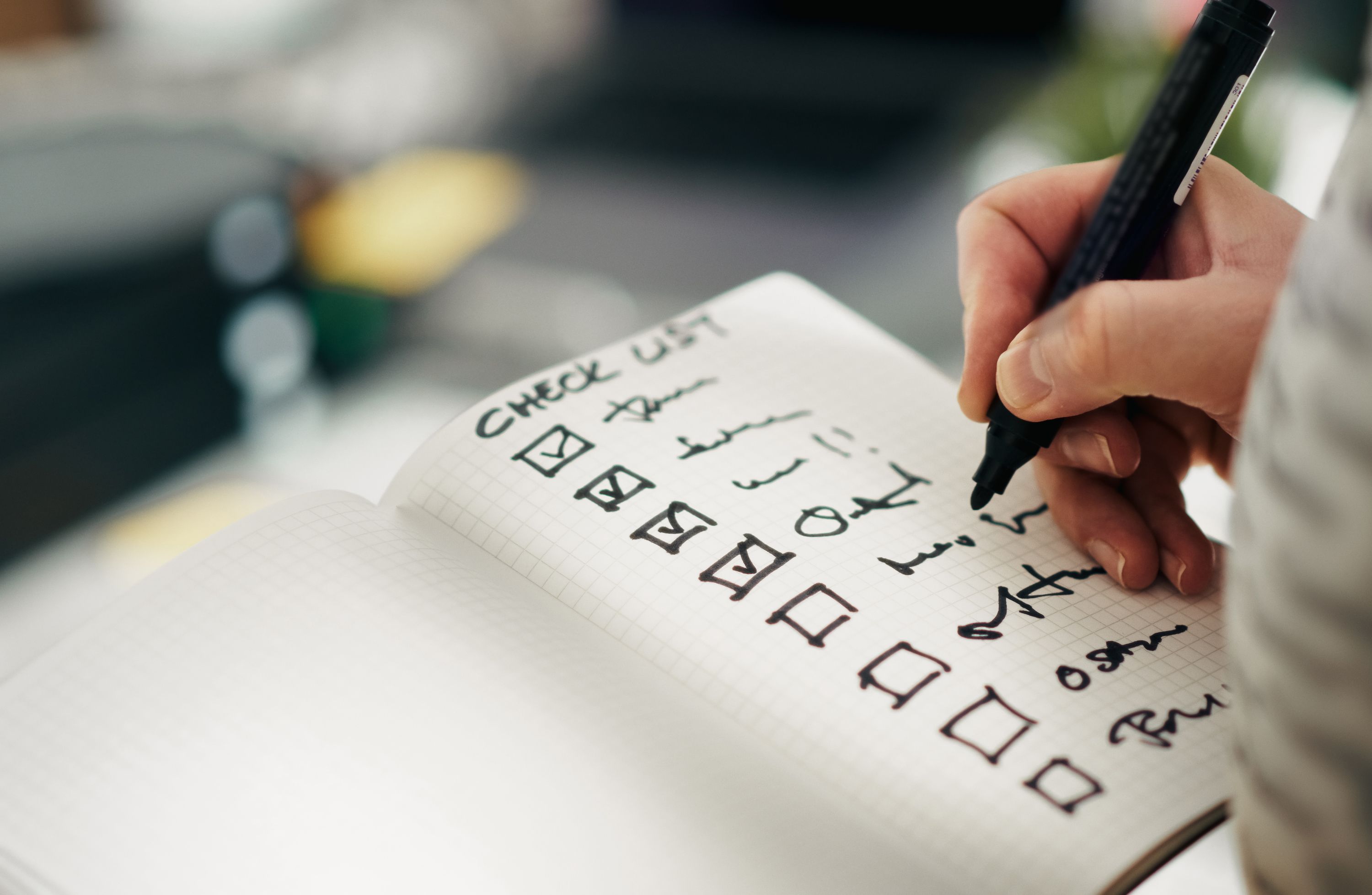 Caderno com checklist manuscrito sendo preenchido à mão