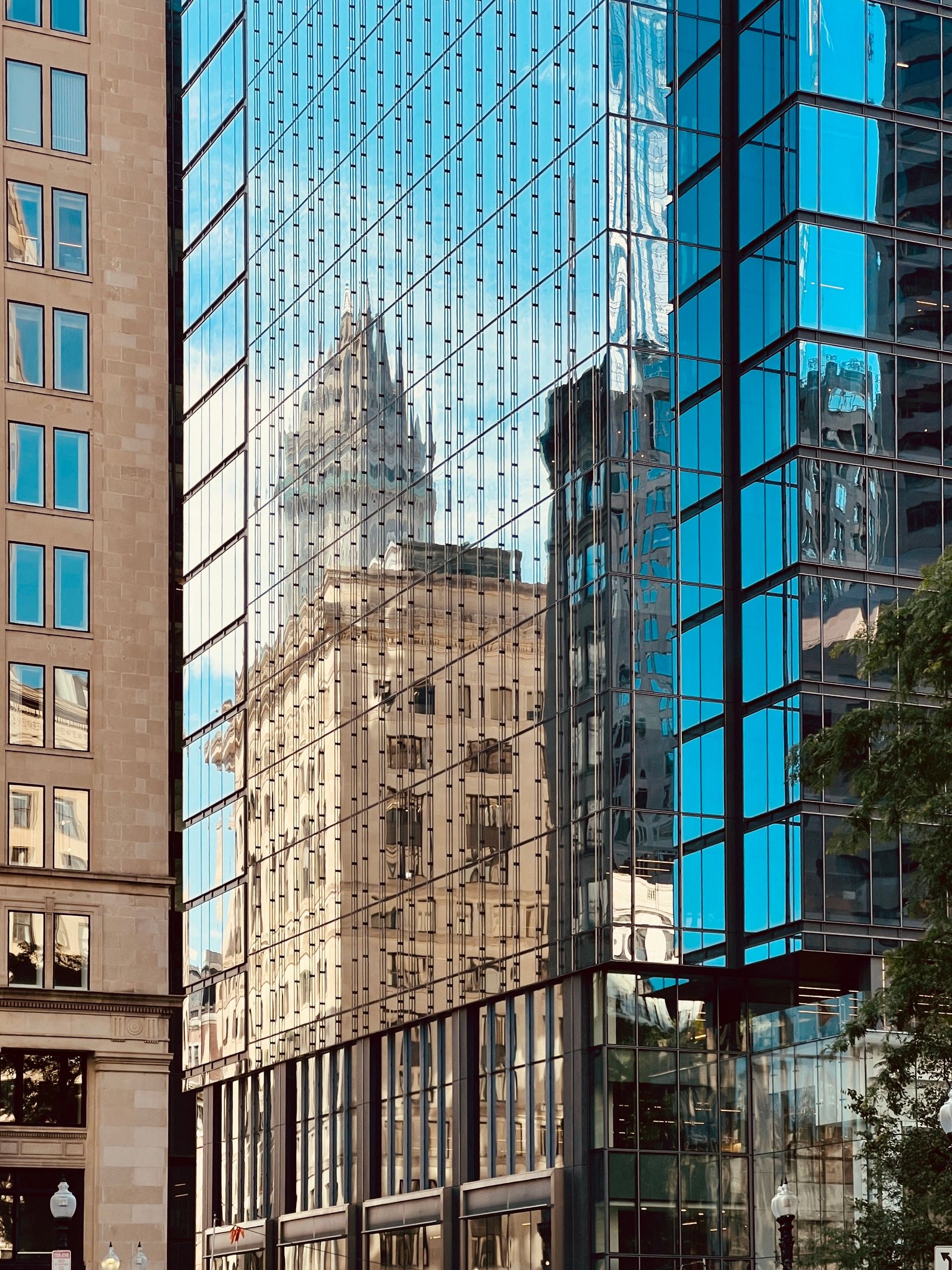 Reflexo de um prédio histórico na fachada de vidro de um edifício moderno, simbolizando uma operação nova nascendo ao lado da estrutura legada
