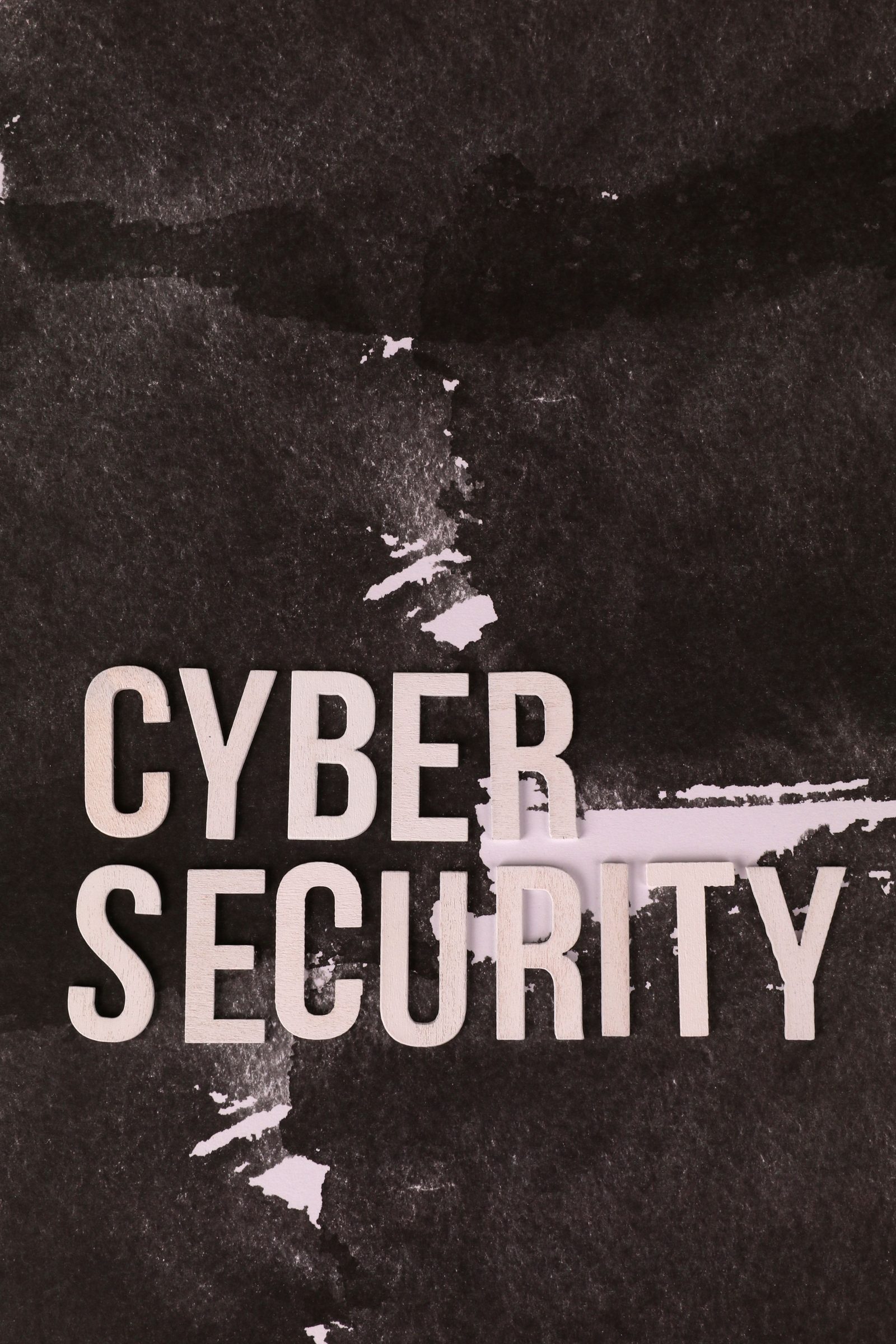 Letras de madeira formando as palavras 'cyber security' sobre fundo escuro rasgado