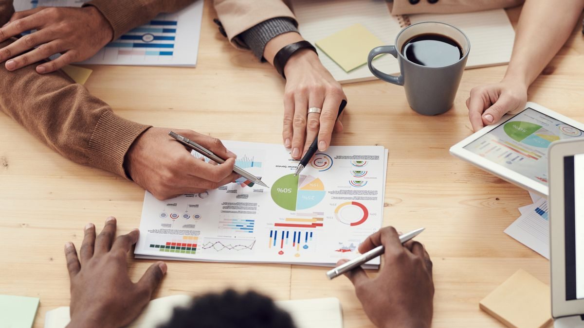 Equipe revisando gráficos e indicadores lado a lado em uma mesa de reunião, simbolizando comparação de portfólio